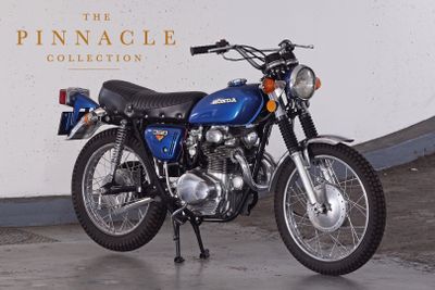 a blue motorcycle parked in front of the pinnacle collection sign