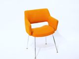 une chaise orange posée sur un sol blanc, à côté d'un mur blanc
