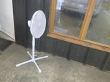 un ventilateur blanc posé sur le trottoir devant un immeuble