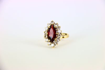 a gold ring with a red stone surrounded by white diamonds