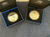 two silver and gold coins in a black box on a blue surface