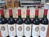 six bouteilles de vin rouge sont alignées sur une table