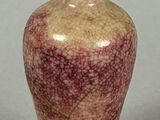 a small vase with a green lid sitting on a table