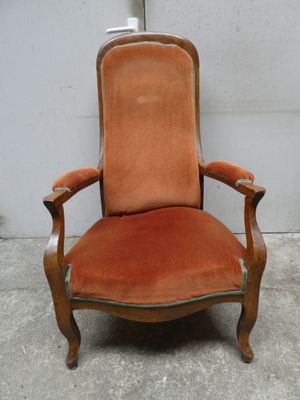 une chaise orange posée sur un sol en béton, près d'un mur blanc