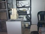 a small refrigerator in the corner of a room with a lot of clutter on the floor