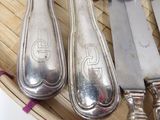 a lot of silver spoons and knives in a basket