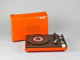 un tourne-disque orange à côté d'une radio orange, posés sur une surface blanche