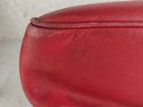 a close up of a red purse on a white surface