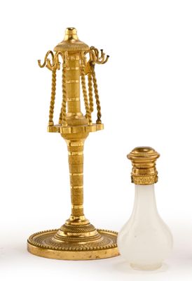 un bougeoir doré et une bouteille en verre sur fond blanc