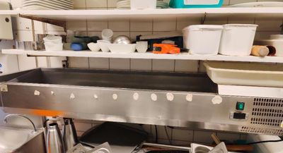un grand évier en métal dans une cuisine où les étagères sont remplies de vaisselle