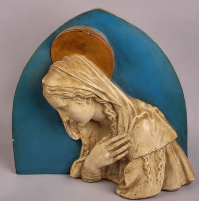 statue d'une femme en prière devant une arche bleue