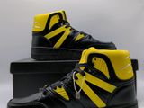 a pair of black and yellow sneakers sitting on top of a box