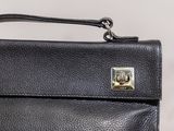 black leather purse with a metal clasp on a white background
