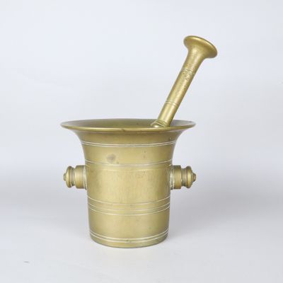 a brass mortar and a pestula on a white background