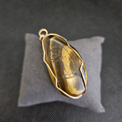 pendentif plaqué or orné d'un gros œil-de-tigre jaune monté sur un coussin