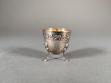 an antique silver cup on a stand on a gray surface