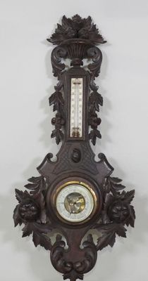 une horloge accrochée au mur, sur laquelle se trouve un thermomètre