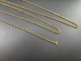 three gold chain necklaces on a black surface