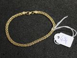 a gold chain bracelet with a tag on a black surface