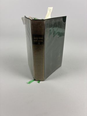 un livre ouvert posé sur une table blanche, à côté d'un ruban adhésif vert