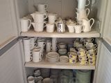 many cups and saucers on the shelves in the kitchen