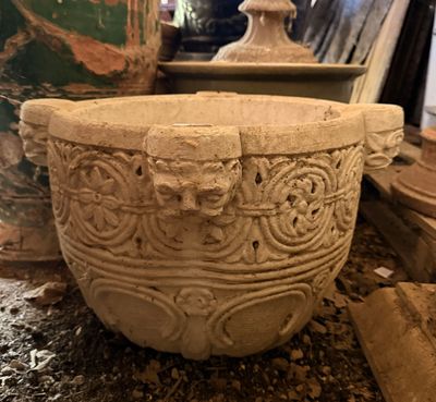 un grand bol en pierre posé par terre à côté d'un vase