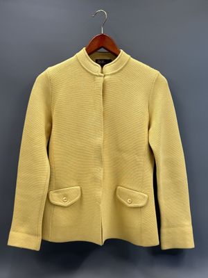 une veste jaune suspendue à un cintre devant un mur gris