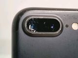 the back of a black phone with a broken camera lens