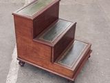 a wooden step stool with a glass top on wheels