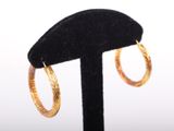 a close up of a pair of gold hoop earrings on a black stand
