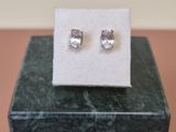 a pair of diamond stud earrings sitting on top of a marble block