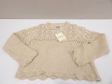the sweater is beige and has a crochet pattern on it