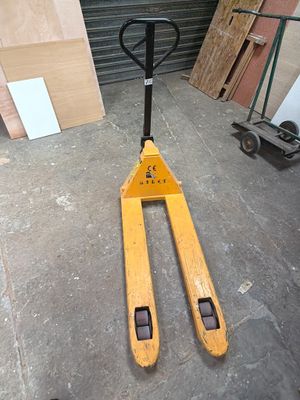 a fork lifter sitting in a garage next to a pile of wood