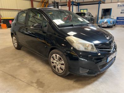 a black car parked in a garage with other cars in the background