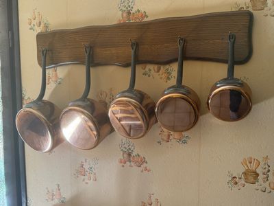 several pots and pans hanging from a wooden rack in a kitchen