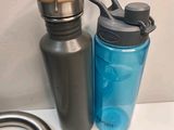 two water bottles sitting next to a faucet on a counter