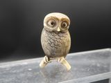 an owl figurine sitting on top of a clear shelf