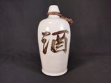 un vase blanc avec une inscription marron sur fond noir