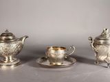 deux théières en argent et une tasse posée sur une soucoupe