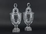two clear glass vases with lids on a black background