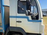 un camion bleu et blanc garé devant un immeuble