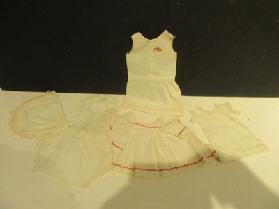 une robe blanche avec des bordures rouges posée sur une table blanche