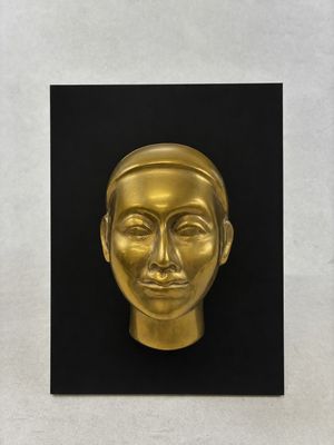 a gold sculpture of a man ' s face on a black background