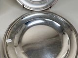 two silver plates sitting on top of a white table