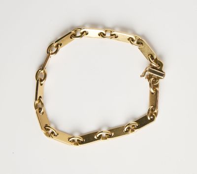 gros plan d'un bracelet en chaîne en or sur une surface blanche