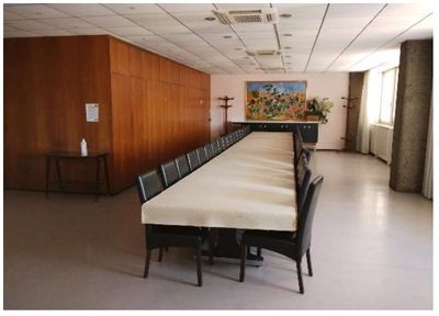 une longue table avec des chaises dans une pièce où est accroché un tableau au mur
