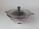 silver plated casserole with glass lid on a white surface