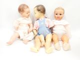 three dolls sitting next to each other on a white surface