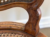 the back of a wooden chair with a wicker seat