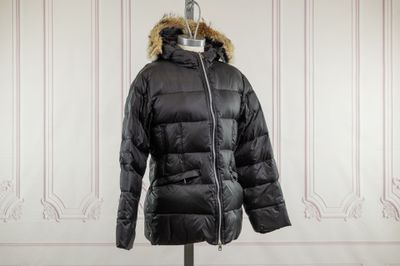 La veste est noire et possède une capuche doublée de fourrure.